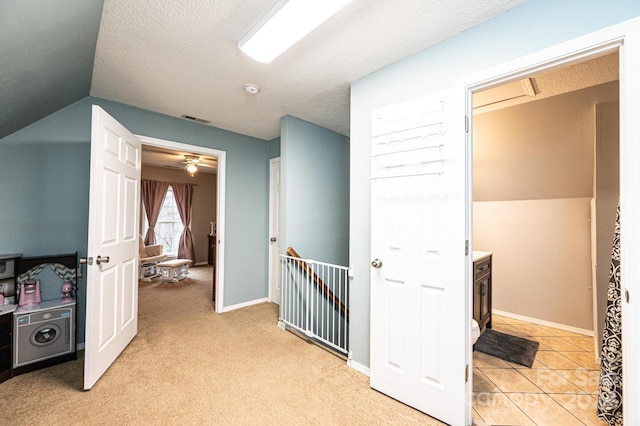 corridor with a textured ceiling, light colored carpet, and lofted ceiling