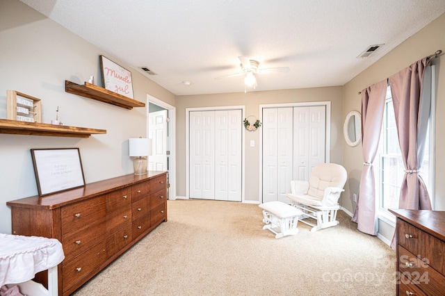 living area with a textured ceiling, ceiling fan, and light carpet