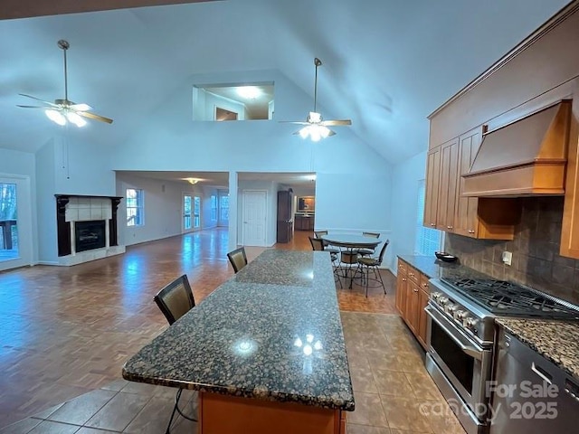 kitchen featuring a kitchen breakfast bar, tasteful backsplash, high end stove, a kitchen island, and custom exhaust hood