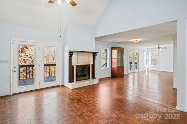 unfurnished living room with ceiling fan, a healthy amount of sunlight, a fireplace, and high vaulted ceiling