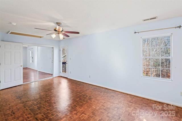 spare room with dark parquet flooring, ceiling fan, and a textured ceiling