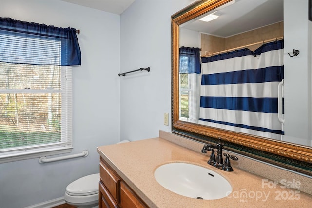 bathroom with walk in shower, a wealth of natural light, vanity, and toilet