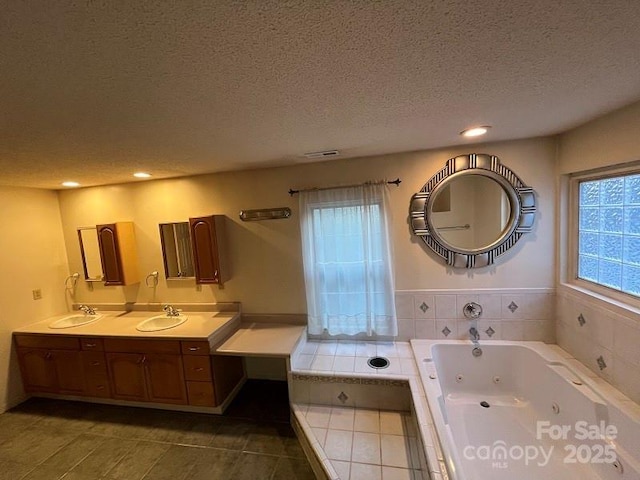 bathroom with vanity, a textured ceiling, tile patterned flooring, and tiled tub