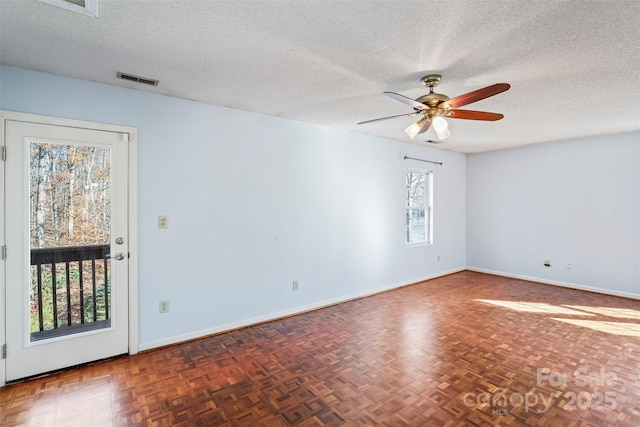 empty room with dark parquet flooring, a textured ceiling, and ceiling fan