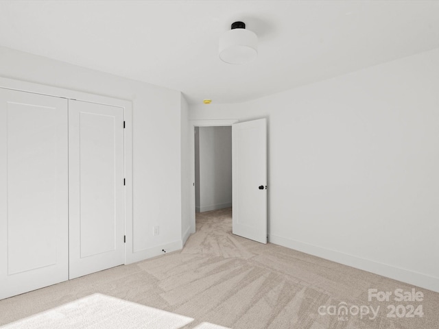 unfurnished bedroom with light carpet and a closet