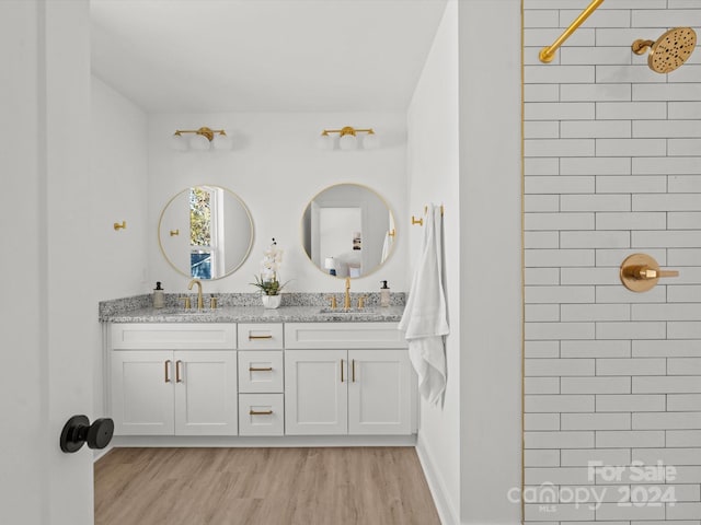 bathroom with hardwood / wood-style flooring, vanity, and a tile shower