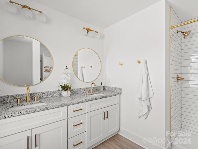 bathroom with a tile shower, hardwood / wood-style floors, and vanity