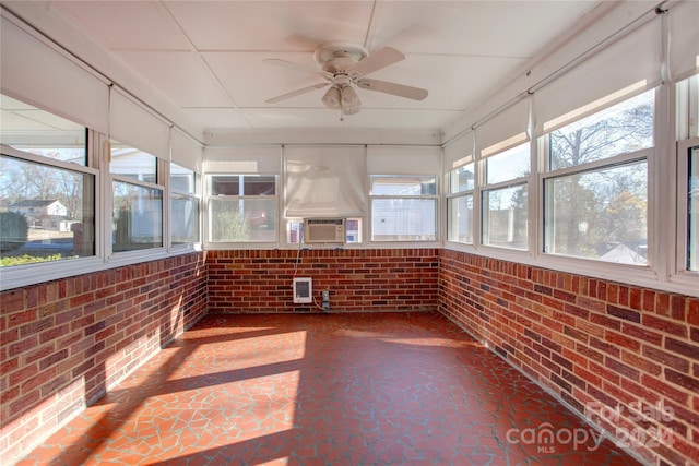 unfurnished sunroom featuring cooling unit, a wealth of natural light, and ceiling fan