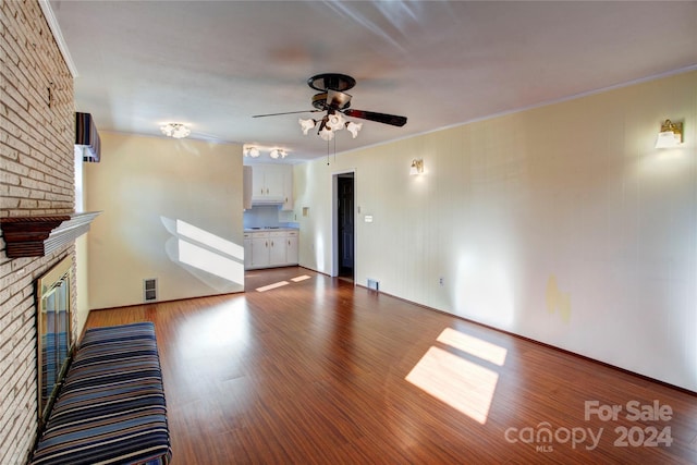 unfurnished living room with ceiling fan, a fireplace, ornamental molding, and hardwood / wood-style flooring