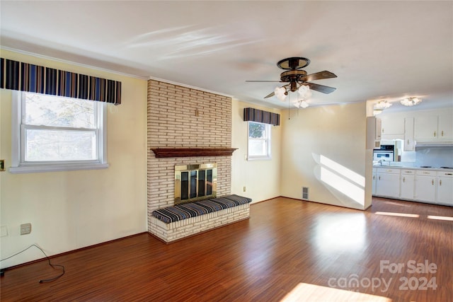 unfurnished living room featuring ceiling fan, hardwood / wood-style floors, crown molding, and a brick fireplace