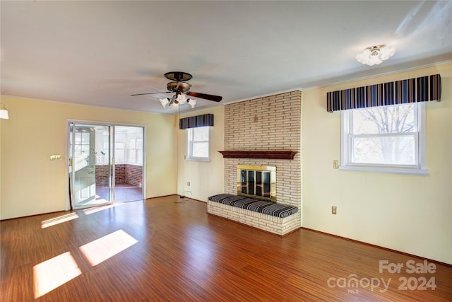 unfurnished living room with dark hardwood / wood-style floors, ceiling fan, a fireplace, and a wealth of natural light