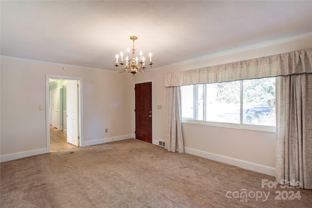 carpeted spare room with crown molding and a chandelier