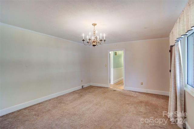 carpeted spare room with a chandelier and crown molding