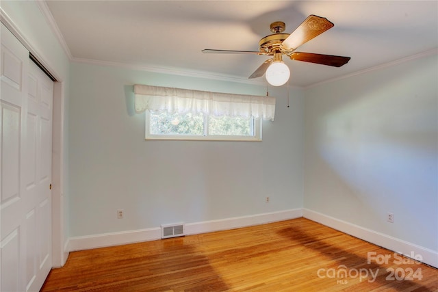 unfurnished bedroom featuring a closet, hardwood / wood-style flooring, ceiling fan, and ornamental molding