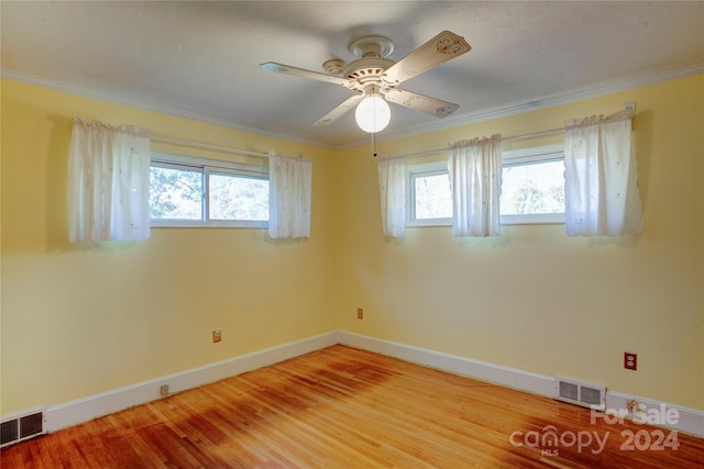 empty room with ceiling fan, wood-type flooring, and crown molding