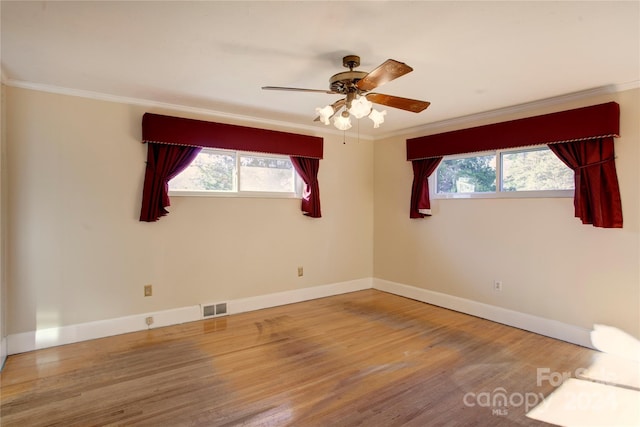 spare room with a healthy amount of sunlight, wood-type flooring, and ornamental molding