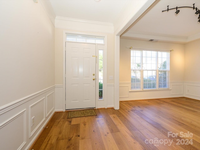 entrance foyer with ornamental molding and light wood-type flooring