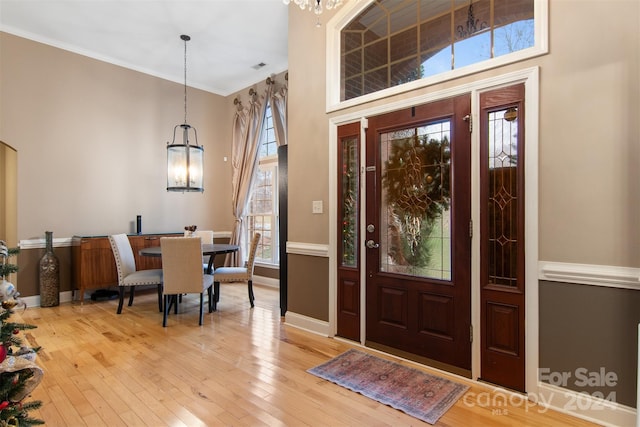 entrance foyer featuring hardwood / wood-style floors, a notable chandelier, ornamental molding, and a towering ceiling