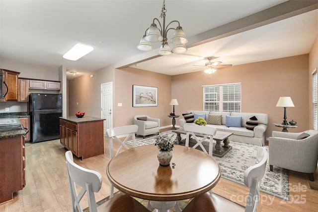 dining room featuring ceiling fan with notable chandelier and light wood-type flooring