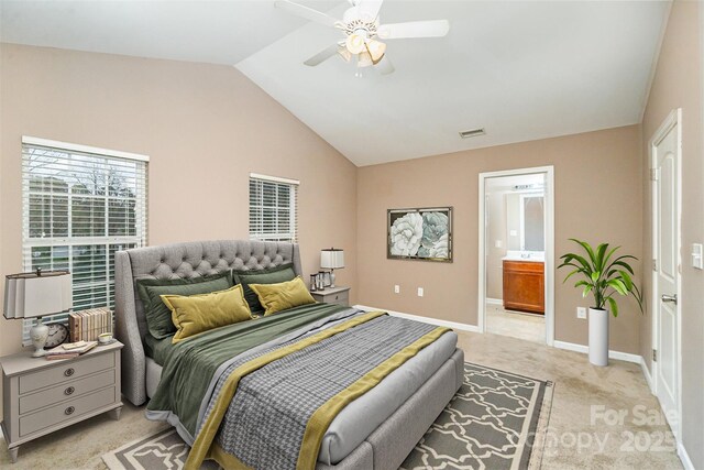 carpeted bedroom with vaulted ceiling, ceiling fan, and ensuite bath