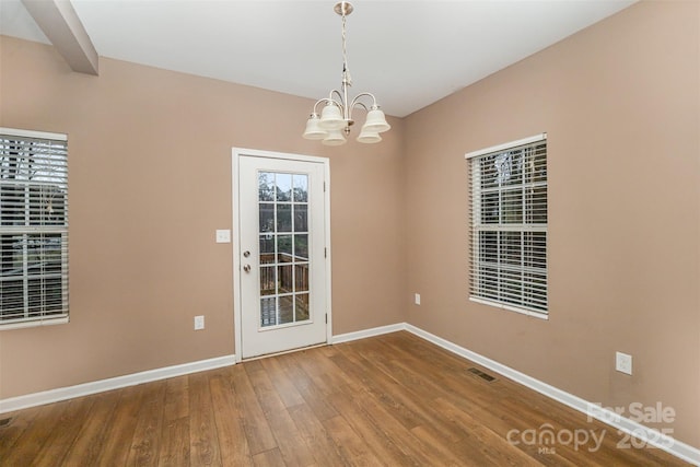 spare room featuring an inviting chandelier and wood-type flooring