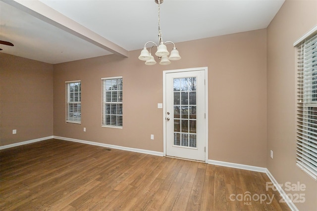 interior space with beam ceiling, wood-type flooring, and a chandelier