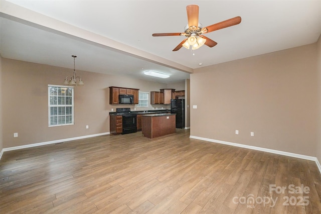 kitchen with decorative light fixtures, a center island, hardwood / wood-style flooring, ceiling fan with notable chandelier, and black appliances