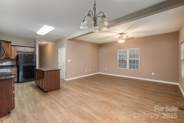 kitchen featuring a center island, black refrigerator, light hardwood / wood-style floors, pendant lighting, and ceiling fan with notable chandelier