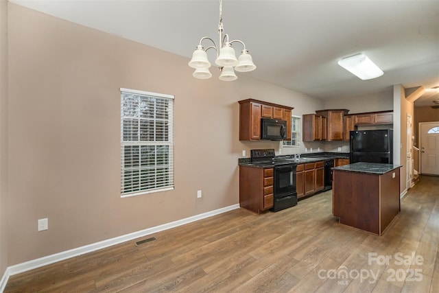 kitchen with decorative light fixtures, a chandelier, a center island, light hardwood / wood-style flooring, and black appliances