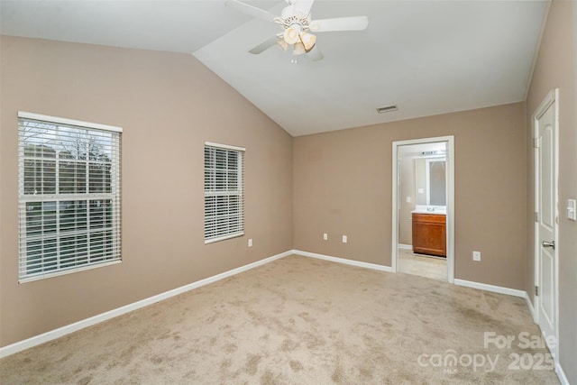 unfurnished bedroom featuring light carpet, lofted ceiling, ceiling fan, and ensuite bathroom