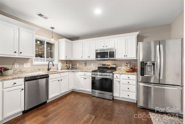 kitchen with dark hardwood / wood-style flooring, stainless steel appliances, sink, decorative light fixtures, and white cabinetry