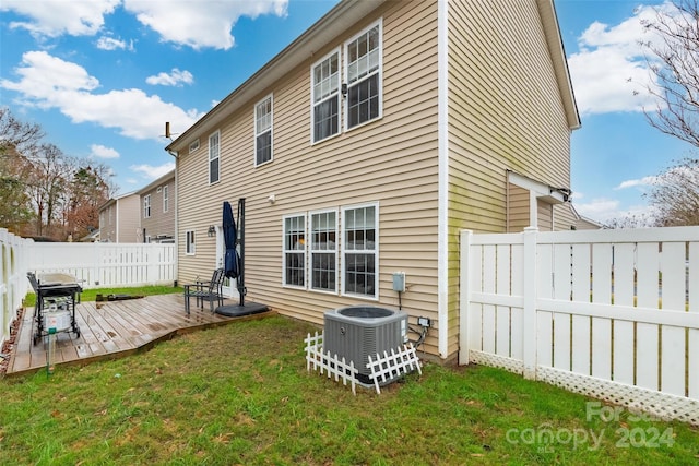 rear view of house with a lawn, cooling unit, and a wooden deck