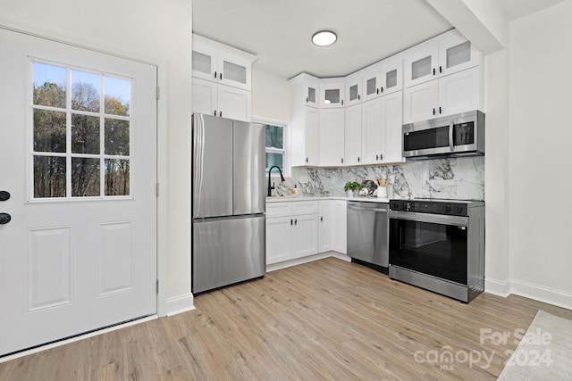 kitchen featuring decorative backsplash, appliances with stainless steel finishes, sink, white cabinets, and light hardwood / wood-style floors