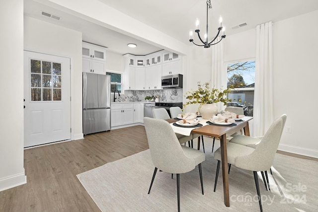 dining room with a chandelier, sink, and light hardwood / wood-style floors