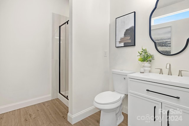 bathroom with vanity, toilet, wood-type flooring, and a shower with door