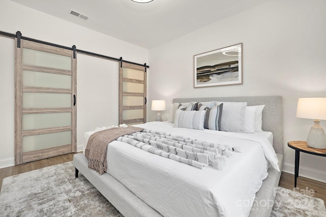 bedroom with a barn door and wood-type flooring