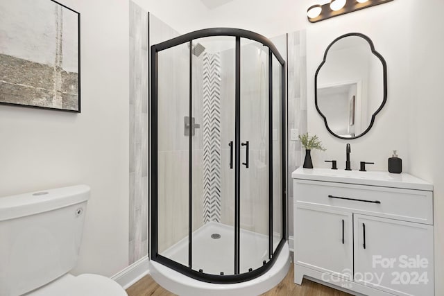 bathroom with hardwood / wood-style floors, a shower with shower door, and toilet