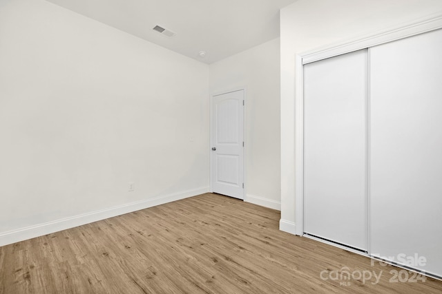 unfurnished bedroom featuring light wood-type flooring and a closet