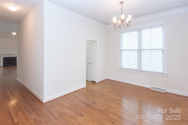 unfurnished room featuring wood-type flooring, crown molding, and a chandelier