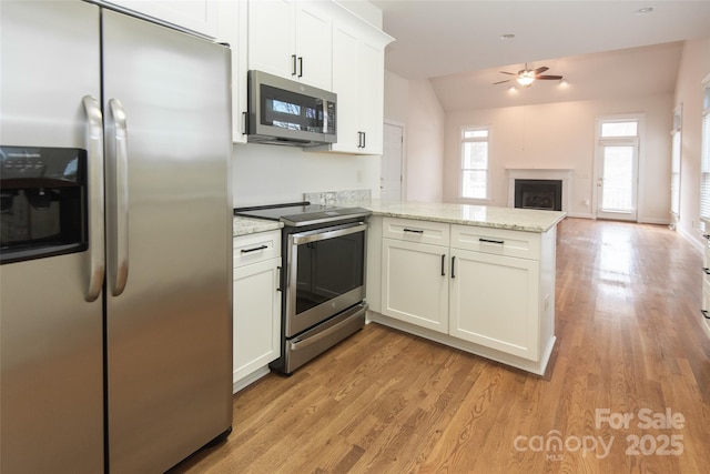 kitchen with white cabinets, light stone countertops, kitchen peninsula, and stainless steel appliances