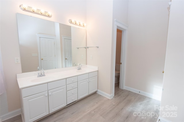 bathroom featuring wood-type flooring, vanity, and toilet