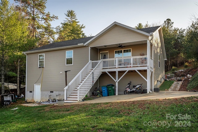 back of property with ceiling fan, a yard, and a porch