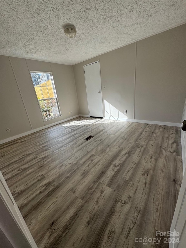 empty room with a textured ceiling and hardwood / wood-style flooring