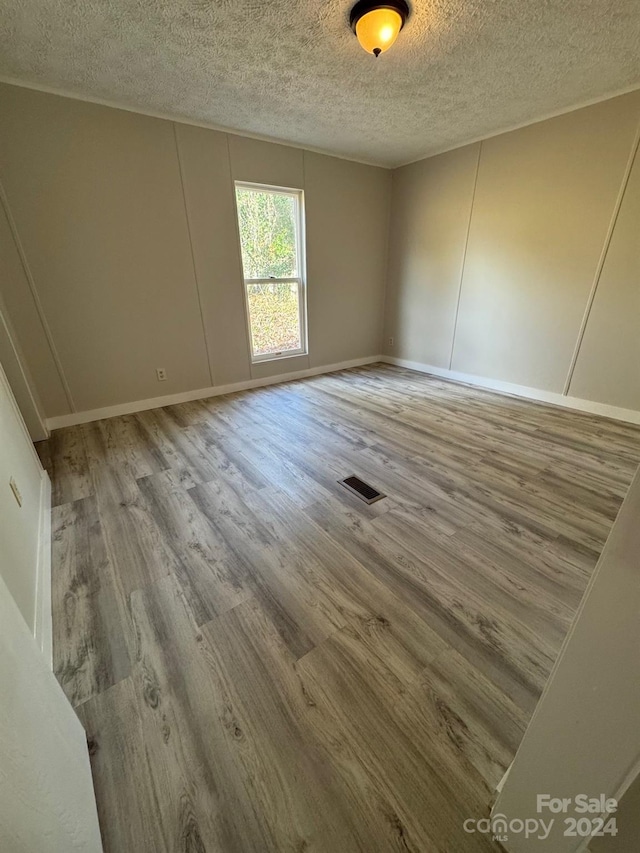 spare room featuring hardwood / wood-style flooring and a textured ceiling