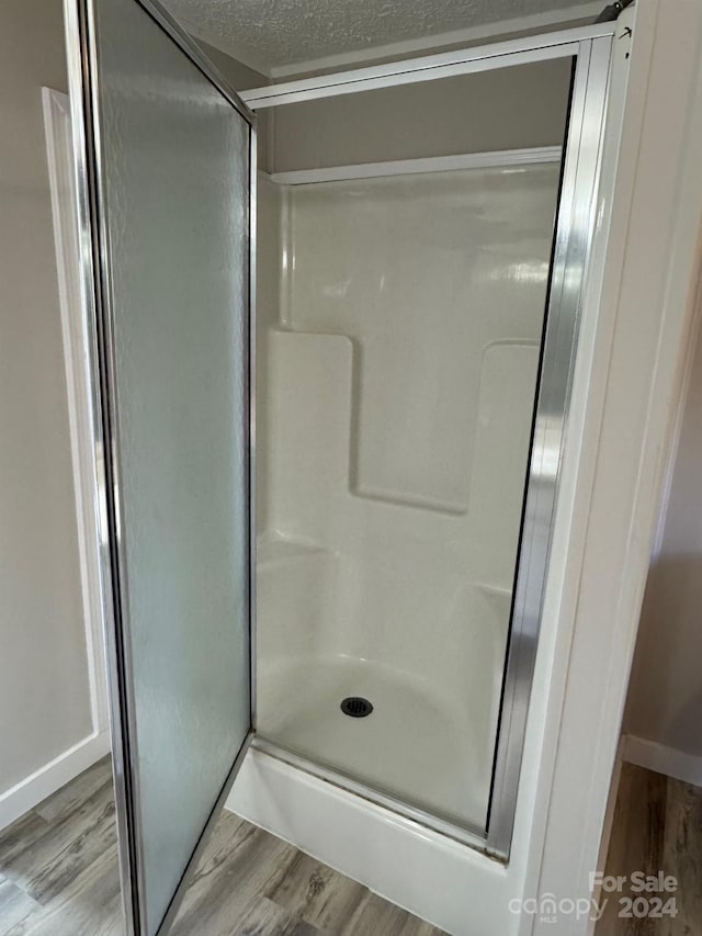 bathroom featuring hardwood / wood-style floors, walk in shower, and a textured ceiling