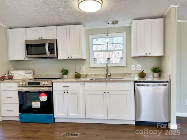 kitchen with pendant lighting, sink, dark wood-type flooring, white cabinetry, and stainless steel appliances