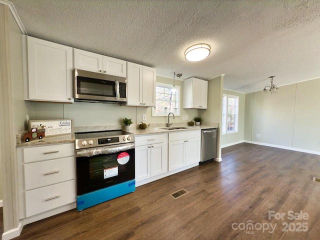 kitchen with sink, stainless steel appliances, white cabinets, dark hardwood / wood-style flooring, and decorative light fixtures