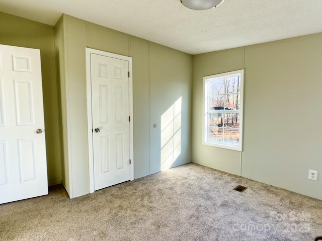 unfurnished bedroom with light carpet and a textured ceiling