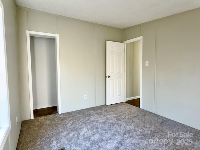 unfurnished bedroom with dark colored carpet