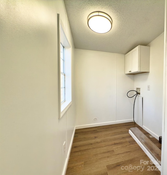 laundry area featuring washer hookup, hardwood / wood-style flooring, cabinets, and a textured ceiling